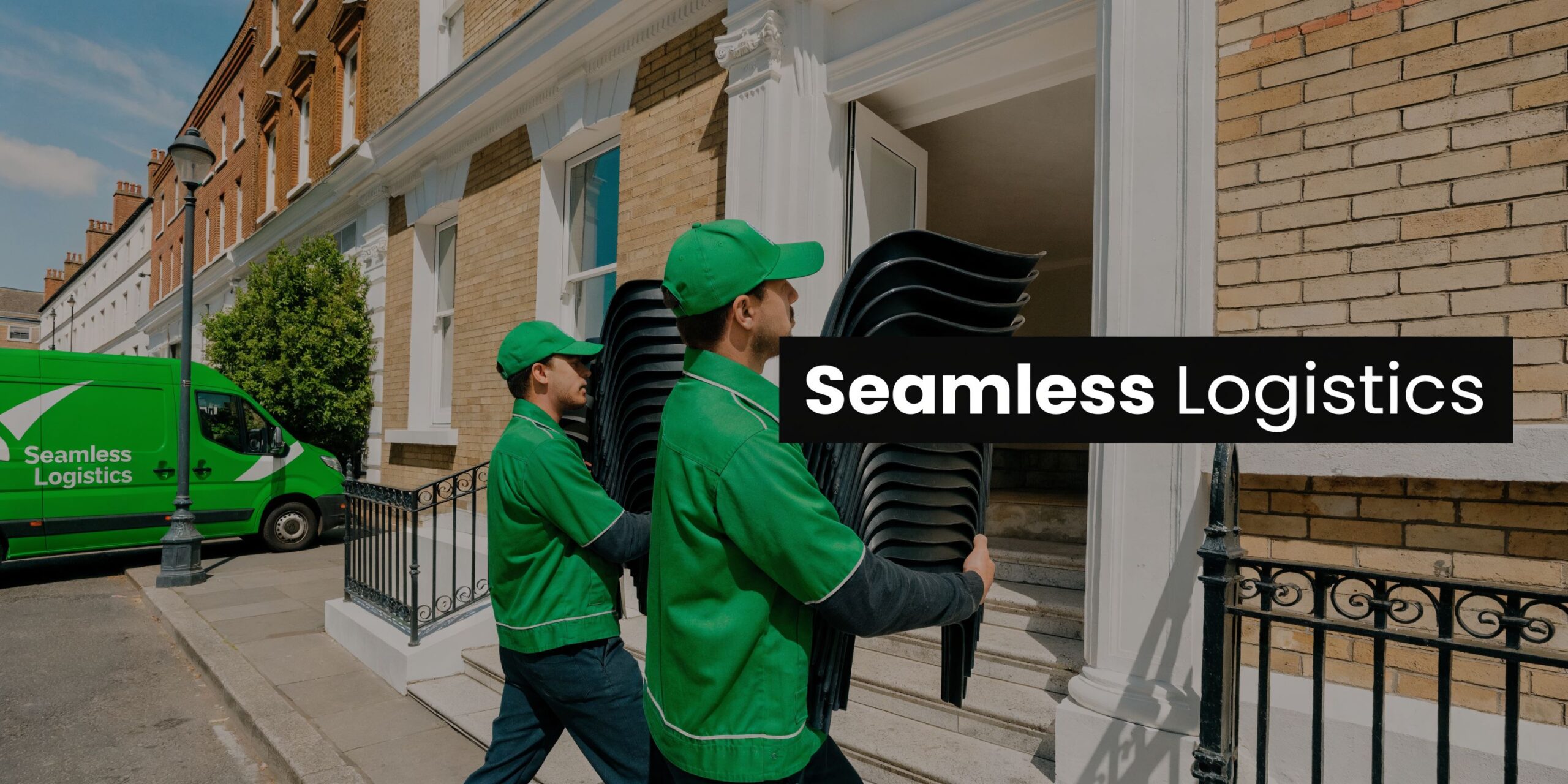 Two logistics workers in green uniforms carrying stacks of black chairs toward a building entrance in London.