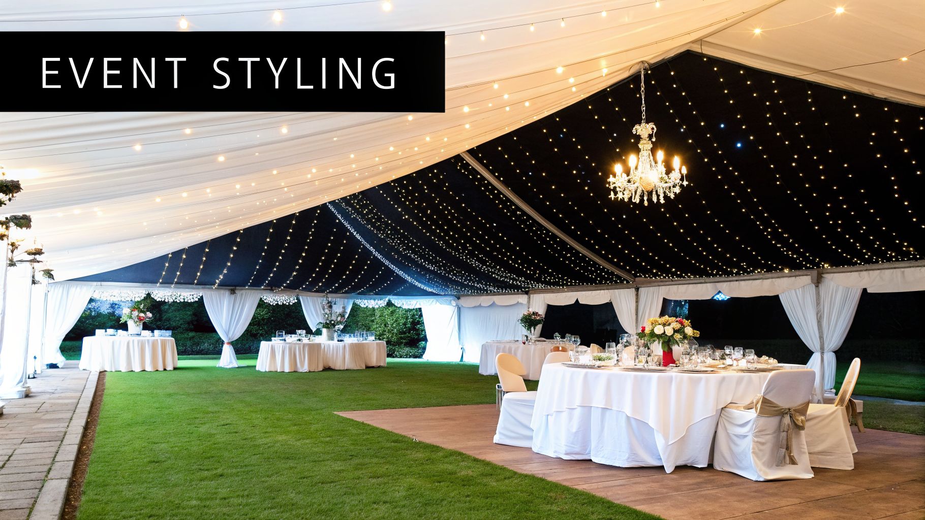 An elegant outdoor event tent at night, featuring string lights, a chandelier, and beautifully set tables.