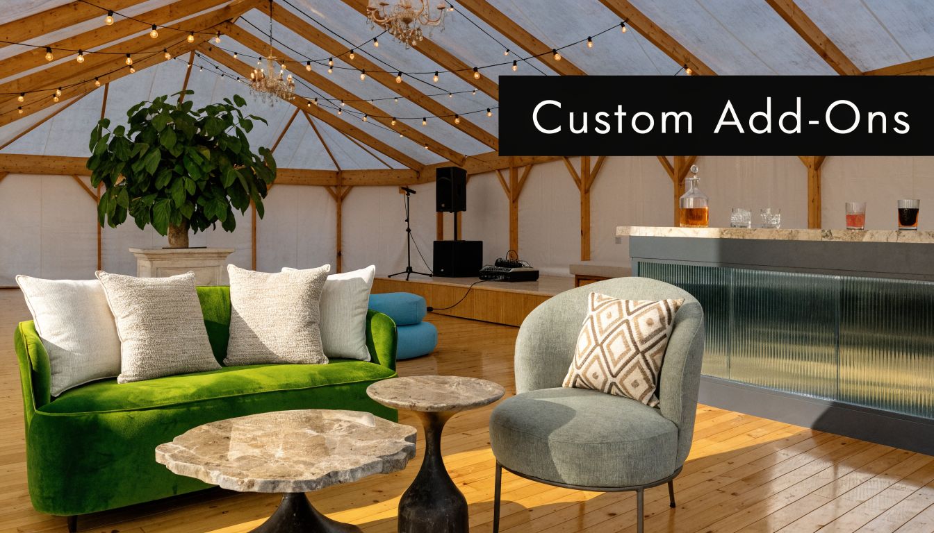 A sophisticated event lounge inside a large marquee featuring a plush green sofa, armchair, and custom bar.