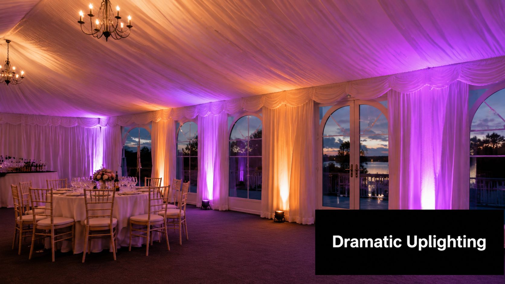 A luxurious tent decorated with vibrant purple and warm orange uplighting, featuring round dining tables for events.