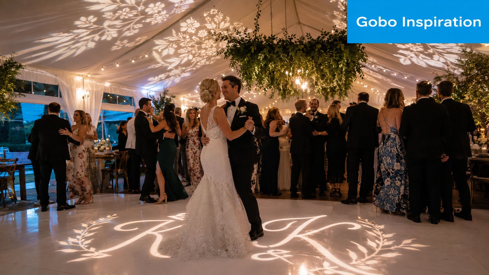 A bride and groom dancing on a white dance floor with a personalized monogram gobo projection.